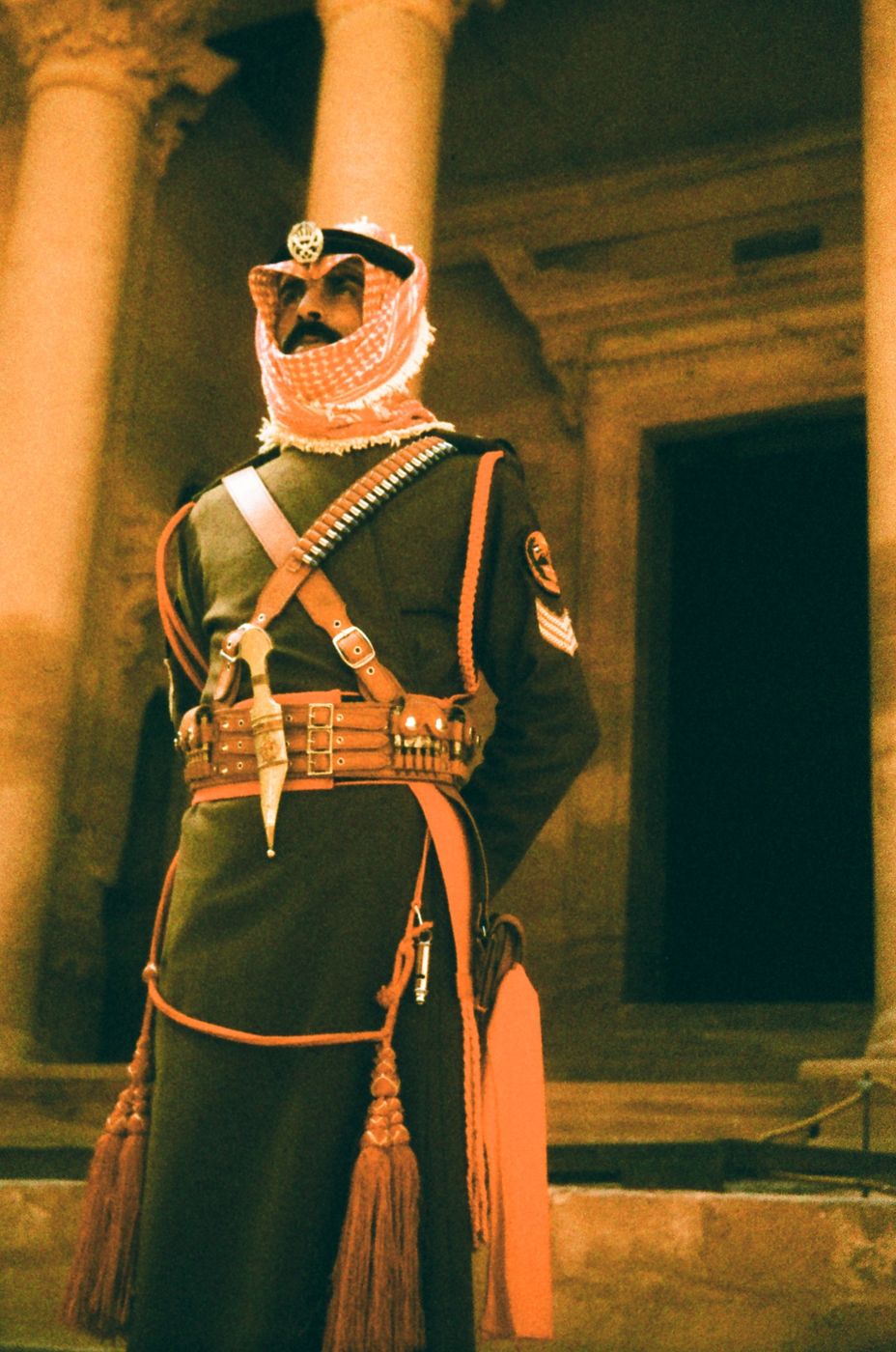 A guard in ceremonial uniform in front of carved stone columns