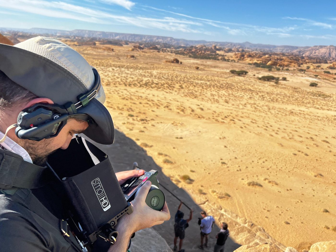 Rian on a clifftop above the Al Ula desert, crew working below