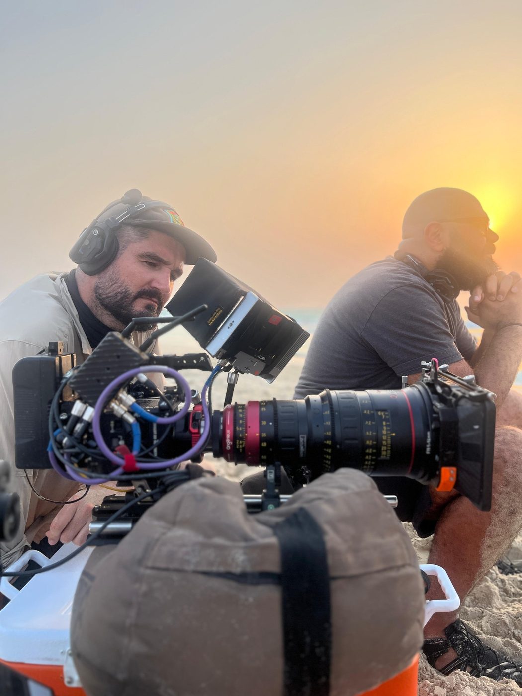 Rian at a camera fitted with a long cine zoom on a beach at sunset