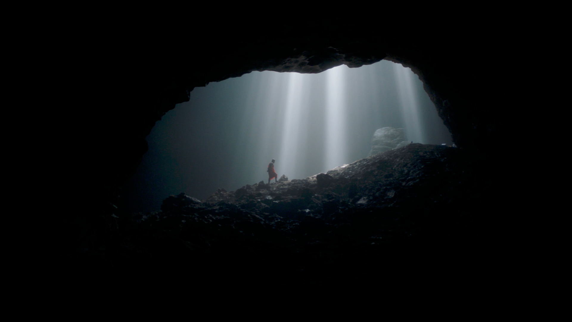 Showreel cover: a figure standing in a beam of light inside a cave